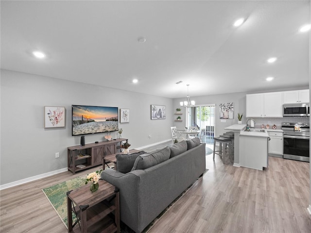 living room with light hardwood / wood-style floors, sink, and a chandelier