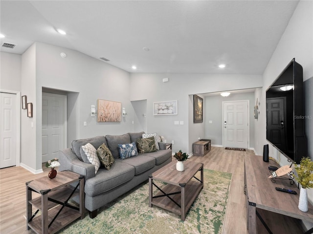 living room with light hardwood / wood-style floors and high vaulted ceiling