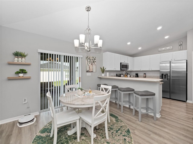 dining room featuring an inviting chandelier, lofted ceiling, and light hardwood / wood-style floors