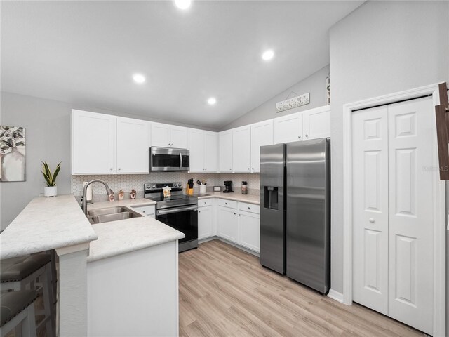 kitchen featuring kitchen peninsula, backsplash, stainless steel appliances, light hardwood / wood-style floors, and sink