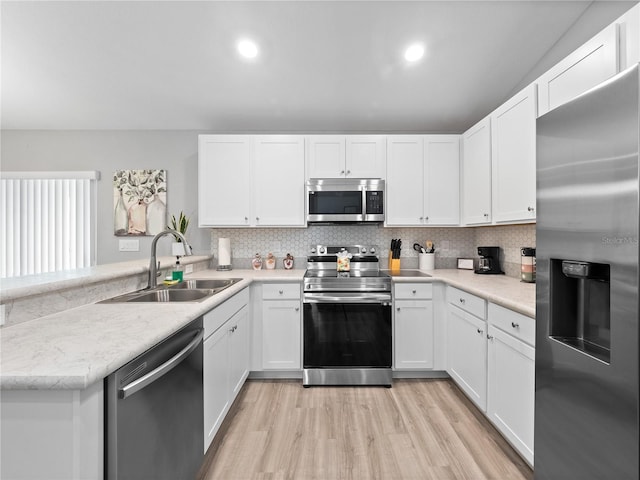 kitchen with stainless steel appliances, backsplash, light hardwood / wood-style flooring, and sink