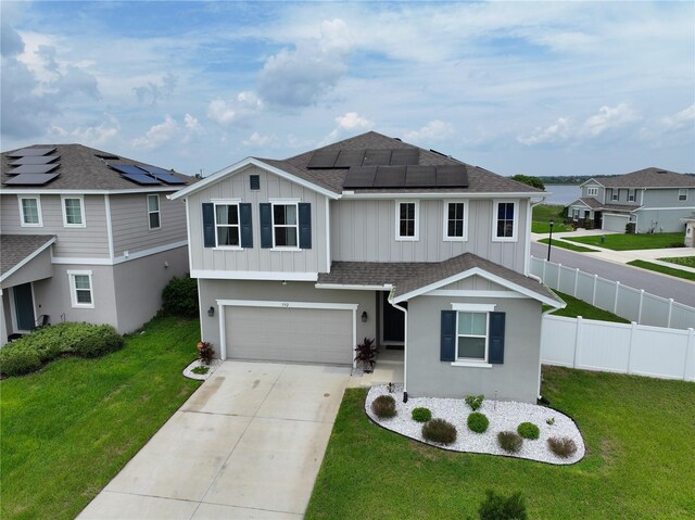 view of front of property featuring a front lawn, solar panels, and a garage