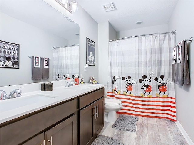 bathroom with visible vents, a sink, toilet, and wood finished floors