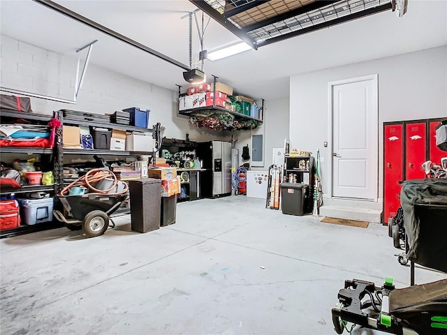 garage featuring concrete block wall, electric panel, stainless steel refrigerator with ice dispenser, and a garage door opener