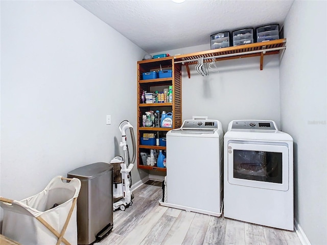 laundry room featuring laundry area, baseboards, washer and clothes dryer, and light wood finished floors