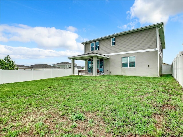 rear view of house featuring a yard, a patio area, and a fenced backyard