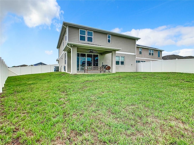 rear view of house with a ceiling fan, a fenced backyard, and a lawn