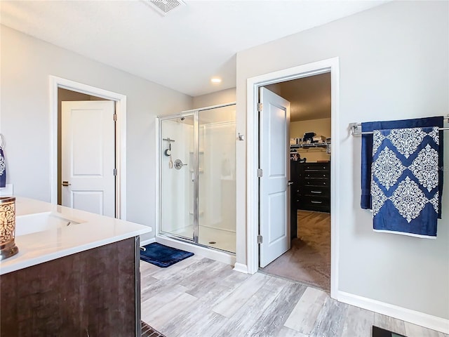 full bathroom featuring visible vents, a spacious closet, a stall shower, vanity, and wood finished floors