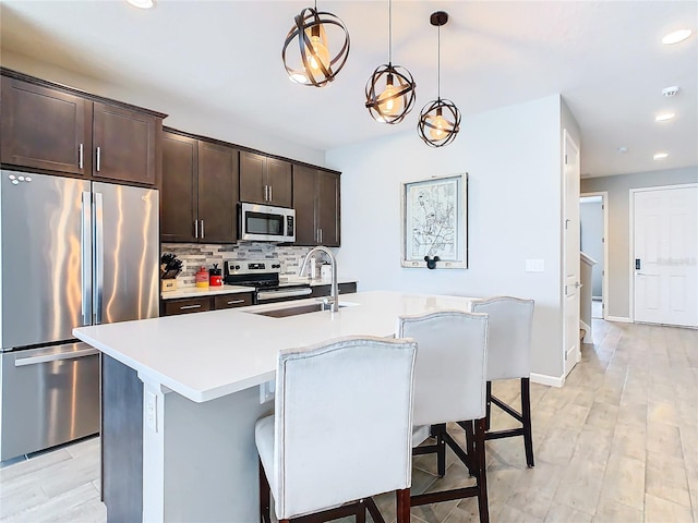 kitchen featuring dark brown cabinetry, backsplash, stainless steel appliances, and a sink