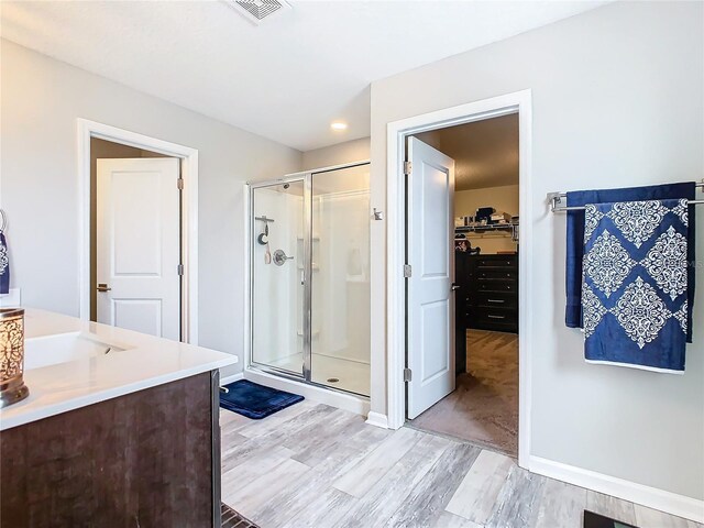 bathroom featuring visible vents, wood finished floors, a spacious closet, vanity, and a shower stall