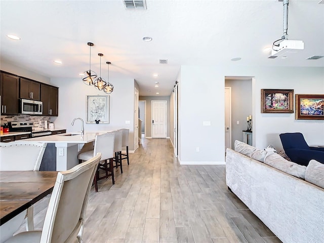 kitchen with visible vents, backsplash, appliances with stainless steel finishes, dark brown cabinetry, and a sink