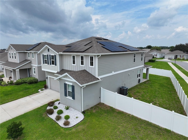 view of front of house featuring a front yard, central AC unit, solar panels, and a garage