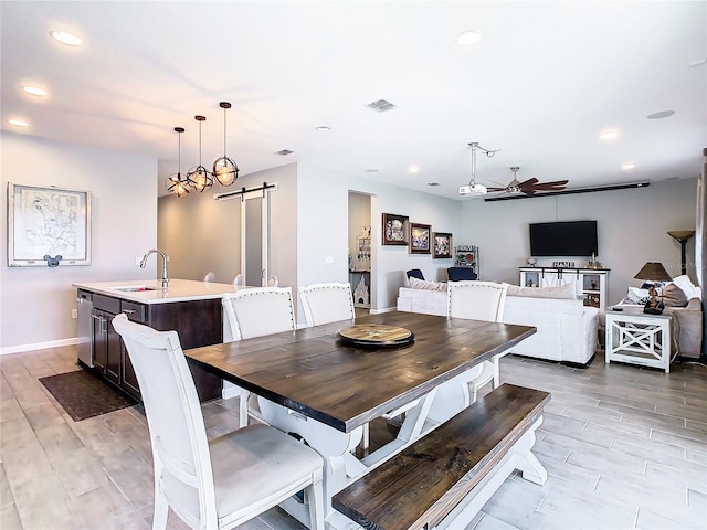 dining space with a barn door, recessed lighting, visible vents, a ceiling fan, and light wood-type flooring