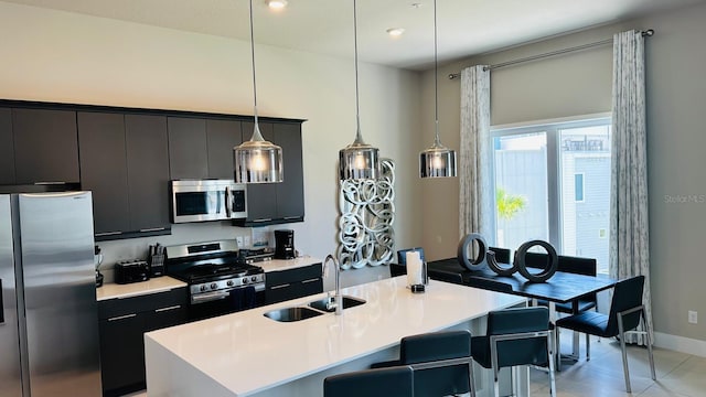 kitchen featuring stainless steel appliances, pendant lighting, sink, a center island with sink, and light tile patterned floors