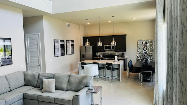 living room with sink, light tile patterned flooring, and a high ceiling