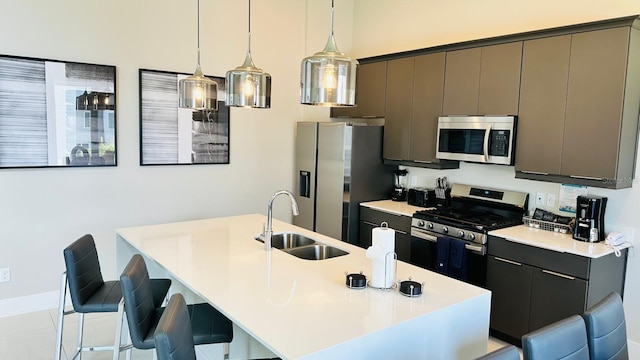 kitchen featuring appliances with stainless steel finishes, a breakfast bar, sink, decorative light fixtures, and an island with sink