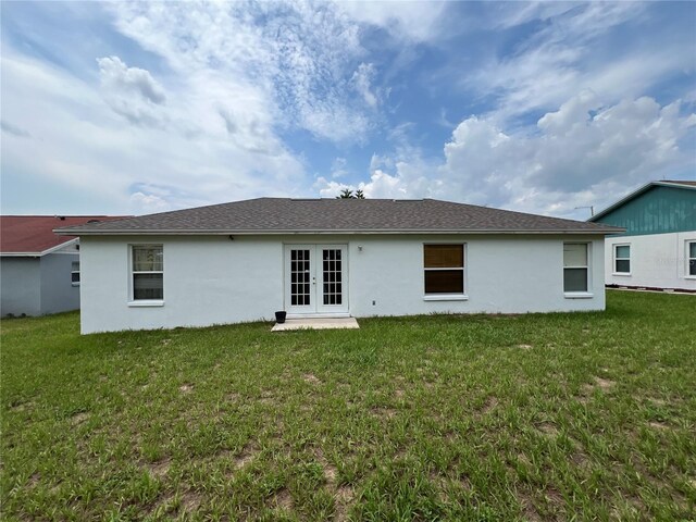 rear view of property featuring a lawn and french doors