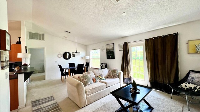 living room with a textured ceiling, light carpet, and vaulted ceiling