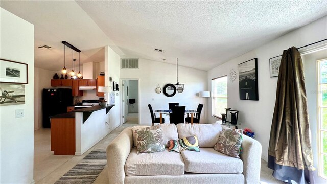 living room featuring vaulted ceiling, a textured ceiling, and an inviting chandelier