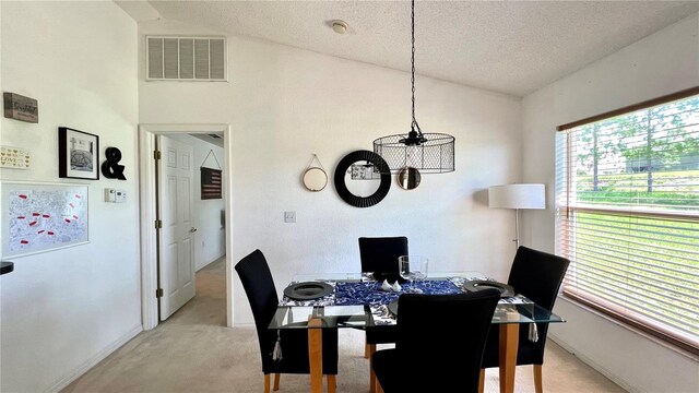 dining area featuring lofted ceiling, a textured ceiling, and light carpet