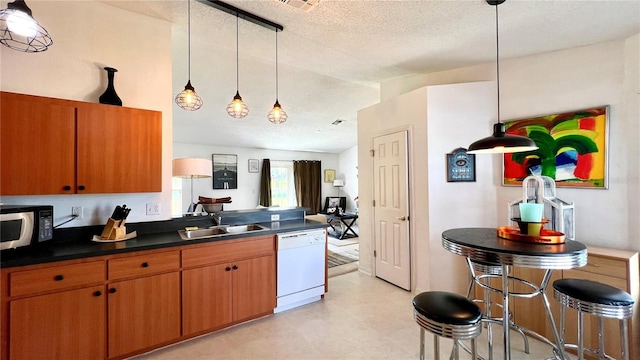 kitchen featuring a kitchen bar, sink, hanging light fixtures, a textured ceiling, and dishwasher