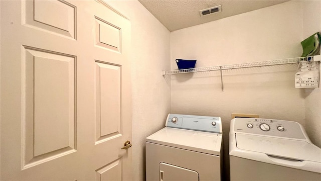 washroom with washer and dryer and a textured ceiling