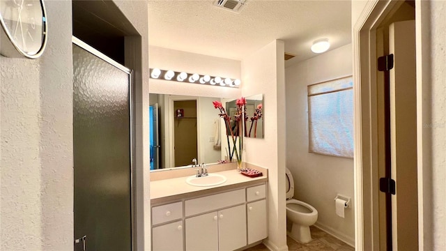 bathroom with vanity, toilet, an enclosed shower, and a textured ceiling