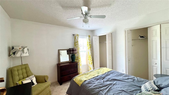 carpeted bedroom with ceiling fan, a textured ceiling, and two closets