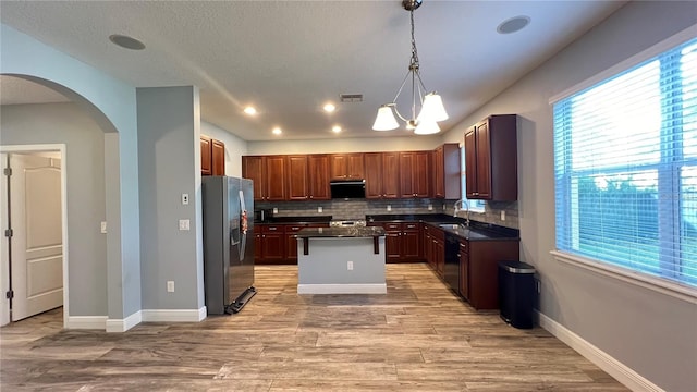 kitchen featuring pendant lighting, sink, black dishwasher, stainless steel refrigerator with ice dispenser, and a kitchen island