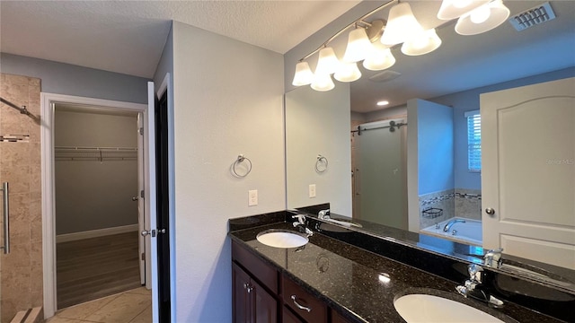 bathroom featuring tile patterned flooring, vanity, a textured ceiling, and separate shower and tub