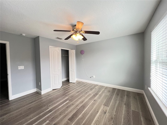 unfurnished bedroom with dark hardwood / wood-style flooring, a textured ceiling, a closet, and ceiling fan