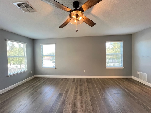 spare room with dark wood-type flooring, plenty of natural light, and a textured ceiling