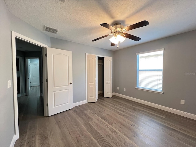 unfurnished bedroom with hardwood / wood-style flooring, ceiling fan, a closet, and a textured ceiling