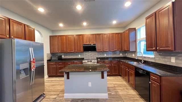 kitchen with a kitchen island, a breakfast bar, sink, dark stone countertops, and stainless steel appliances