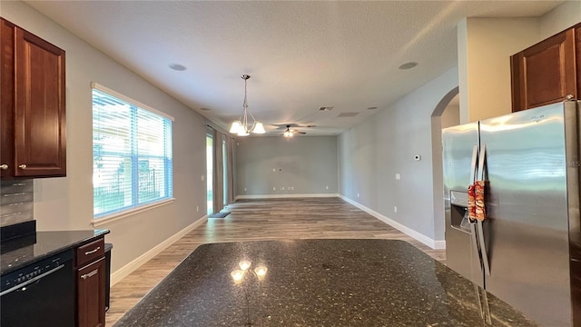 kitchen with stainless steel fridge, dishwasher, decorative light fixtures, dark stone counters, and light wood-type flooring