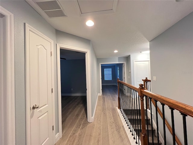 corridor with a textured ceiling and light wood-type flooring