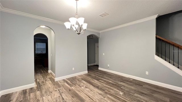 spare room featuring dark hardwood / wood-style flooring, crown molding, a textured ceiling, and an inviting chandelier