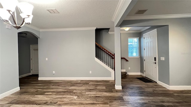 foyer featuring a notable chandelier, ornamental molding, a textured ceiling, and dark hardwood / wood-style flooring