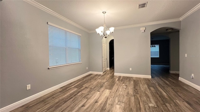 empty room featuring an inviting chandelier, ornamental molding, dark hardwood / wood-style floors, and a textured ceiling