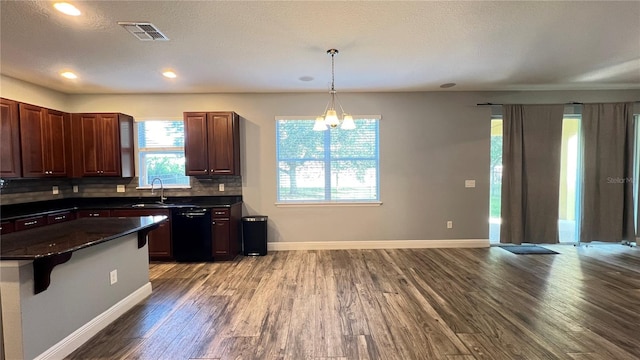 kitchen with dishwasher, backsplash, a kitchen bar, hanging light fixtures, and light wood-type flooring