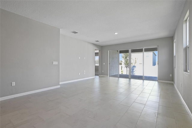 tiled empty room featuring a textured ceiling