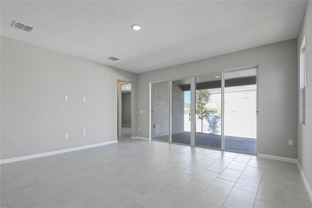 empty room featuring a textured ceiling and french doors