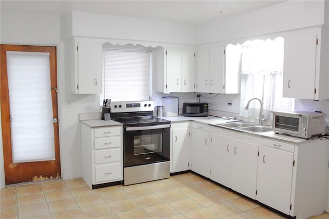 kitchen with electric stove, sink, and white cabinetry