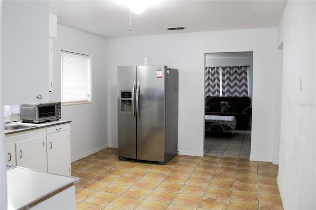 kitchen featuring white cabinetry, stainless steel fridge with ice dispenser, sink, and light tile patterned floors