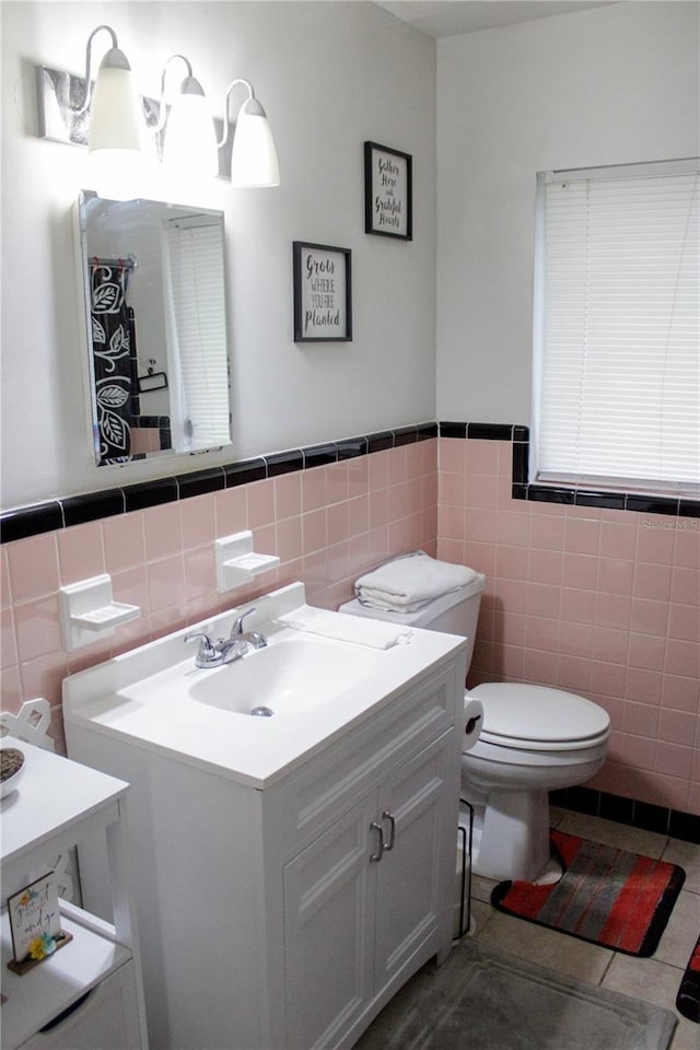 bathroom featuring vanity, tile patterned floors, tile walls, and toilet