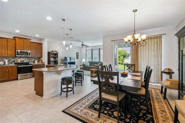 dining room featuring light tile patterned flooring, sink, and ceiling fan with notable chandelier