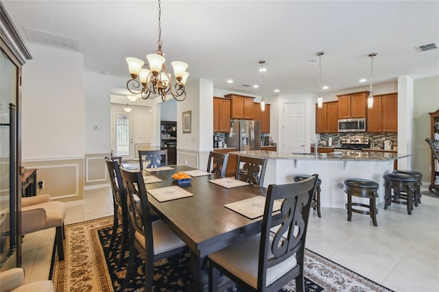 dining room featuring sink, light tile patterned floors, and an inviting chandelier