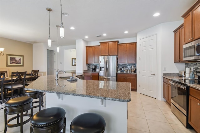 kitchen featuring tasteful backsplash, stainless steel appliances, sink, a kitchen bar, and light tile patterned floors