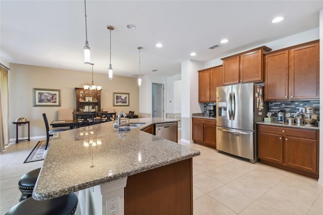 742 San Joaquin Rd, Poinciana, FL 34759 - kitchen featuring a breakfast bar area, stainless steel appliances, a sink, hanging light fixtures, and a large island with sink