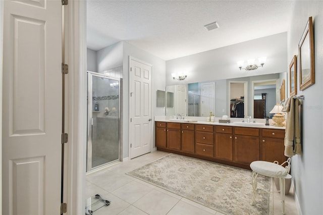 bathroom with a shower with door, a textured ceiling, tile patterned floors, and double sink vanity